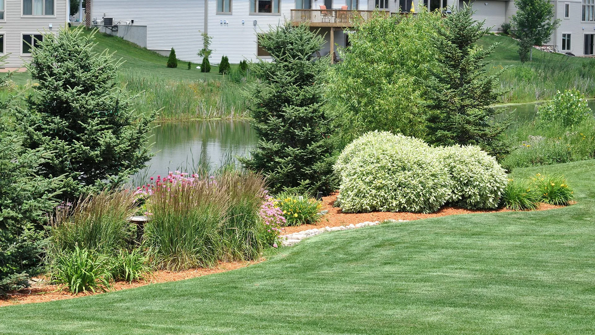 Custom landscaping installed near a body of water at a housing complex in Graham, NC.