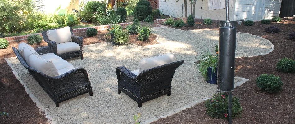 Large patio in Greensboro, NC, with chairs and surrounded by mulch and shrubs.