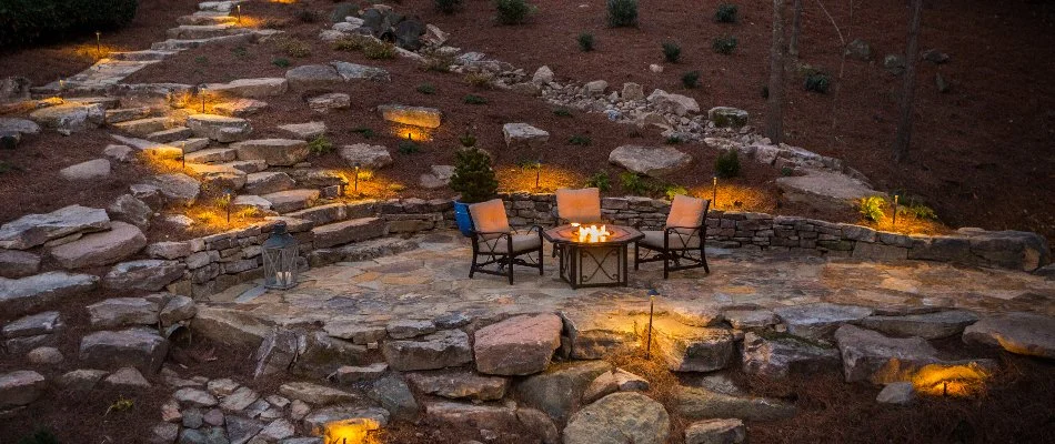 Outdoor steps and retaining wall beside a patio with lighting in Greensboro, NC.