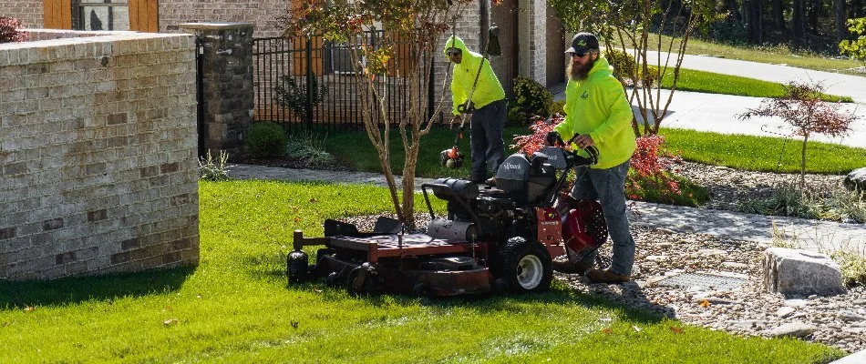 Workers in Greensboro, NC, mowing a lawn and string-trimming.