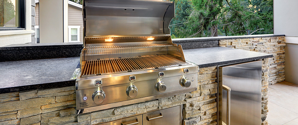 Masterful outdoor kitchen made of stone slabs with a grill built into it near Randleman, NC.