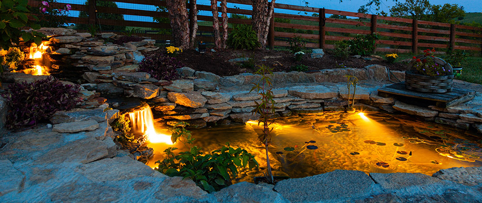A pond and waterfall feature lit up in the evening by a home in Jamestown, NC.