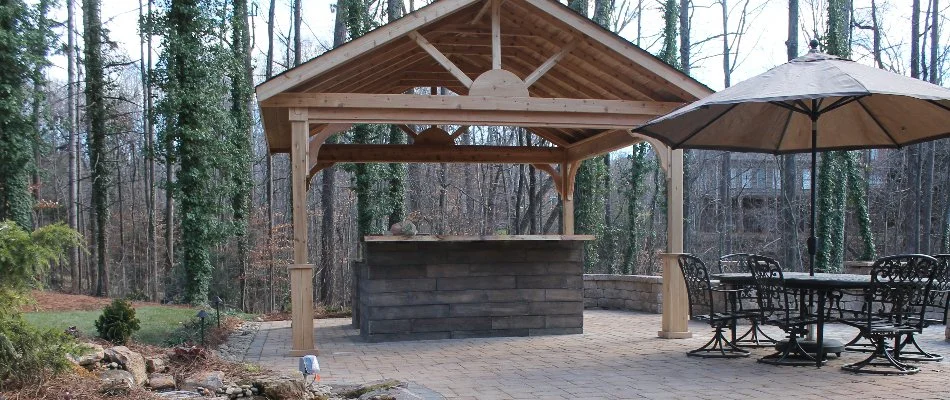 A wooden pavilion on a patio with an outdoor kitchen in Greensboro, NC.