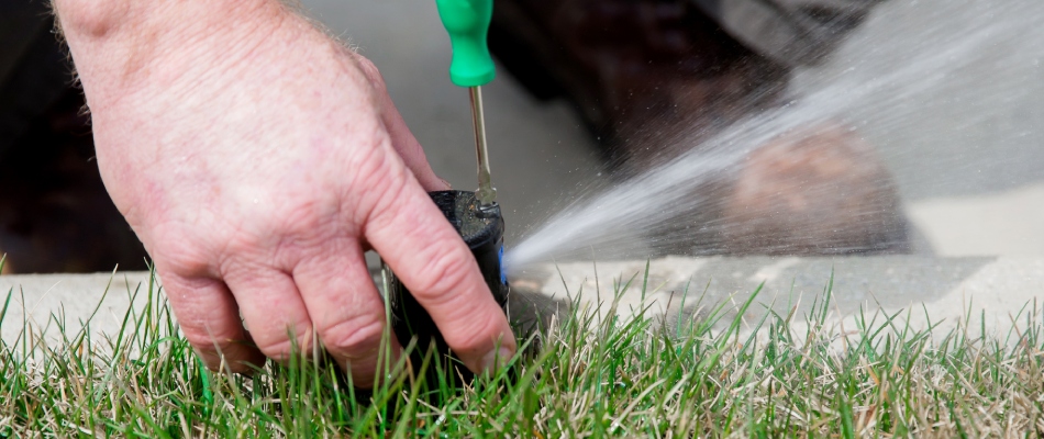 A professional repairing a faulty irrigation sprinkler in lawn in Oak Ridge, NC.