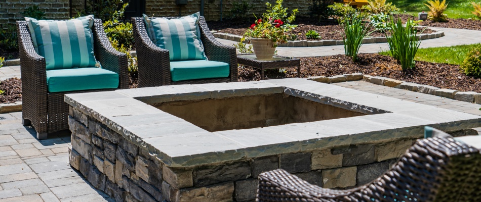 A stone fire pit installed by seating area in backyard in Clemmons, NC.
