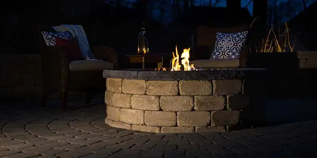 Custom fire pit with flames at night near Summerfield, NC.
